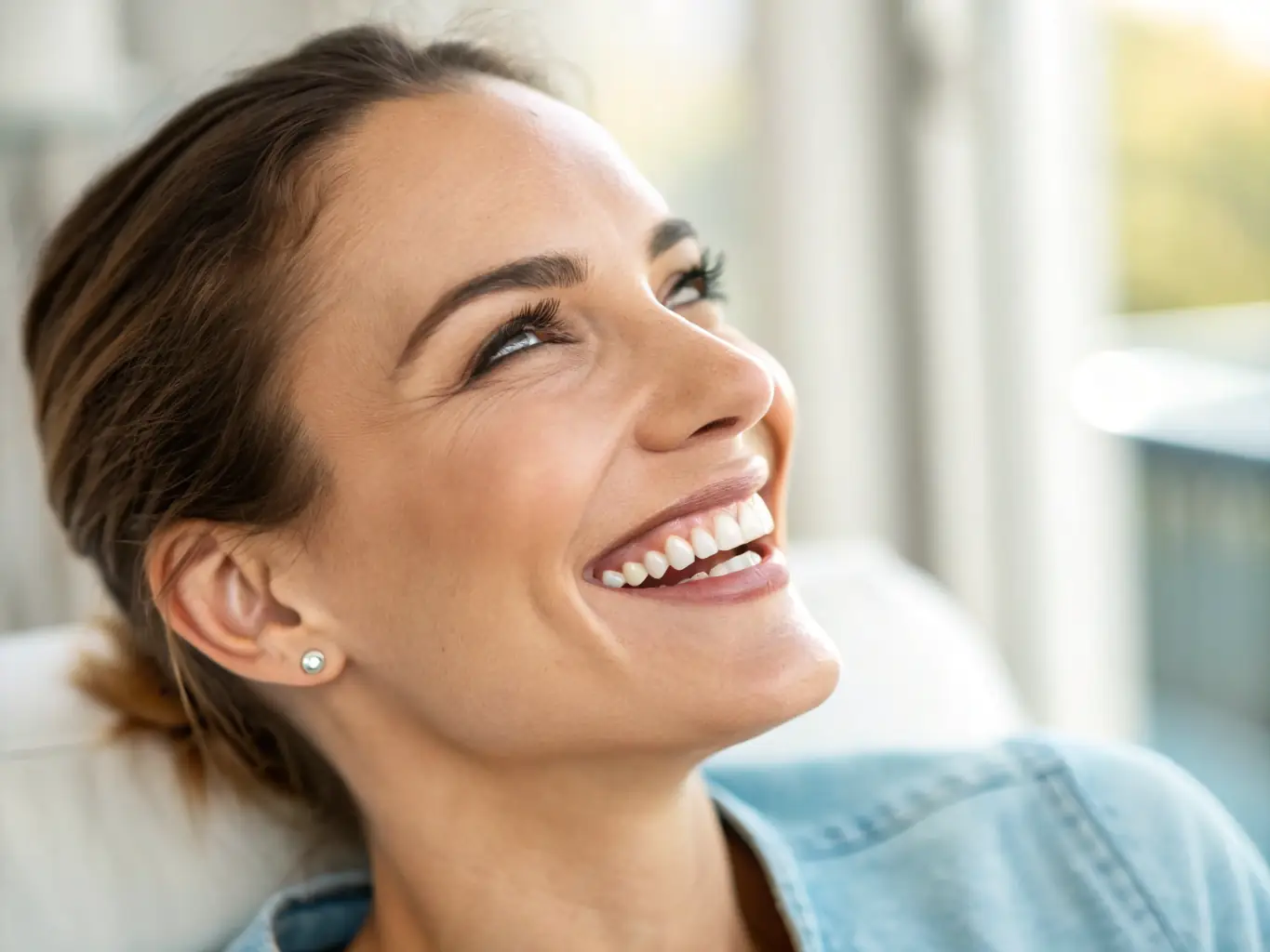 A patient smiling broadly after receiving a full smile makeover, showcasing a complete transformation of their teeth. The image should convey happiness, confidence, and the artistry of the dental work.